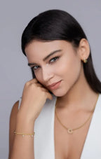 Model wearing a delicate gold bracelet and matching jewelry, photographed in a refined studio setting
