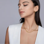 Woman wearing a gold necklace and earrings against a gray background