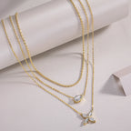 Two gold necklaces with pendants on a light gray background