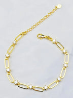 Gold bracelet with diamond-like stones on a light gray background