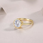 Gold ring with a clear gemstone on a light pink background