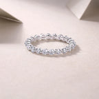 Silver ring with diamonds on a light pink background