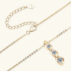 Gold necklace with a heart-shaped clasp and three diamond-like stones on a white background