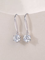 Silver earrings with clear gemstones on a beige background