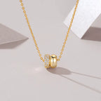 Gold pendant necklace with pavé moissanite accent on a delicate chain displayed against a soft neutral background