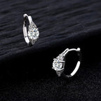 Pair of silver hoop earrings with clear gemstones on a dark background
