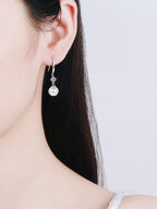 Pearl earring worn by a person on a plain background