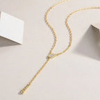 Gold necklace with a delicate chain and heart-shaped pendant on a light background