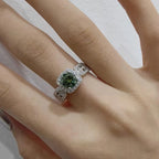 Close-up of a hand wearing a green gemstone ring with diamond accents.