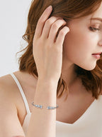 Woman wearing silver earrings and bracelet on a plain background