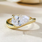 Gold ring with a pear-shaped diamond on a light background