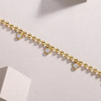 Gold bracelet with small diamonds on a light pink background