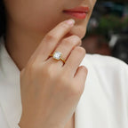 Close-up of a hand wearing a gold ring with a diamond on a blurred background