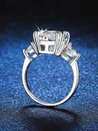 Silver ring with a large central gemstone and smaller stones on a blue textured background