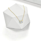 Gold necklace with a diamond pendant on a white geometric stand