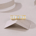 Gold ring with emerald-cut diamonds on a beige background