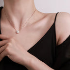 Necklace with a pendant worn by a person, against a neutral background