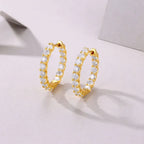 Gold hoop earrings with clear stones on a light gray background