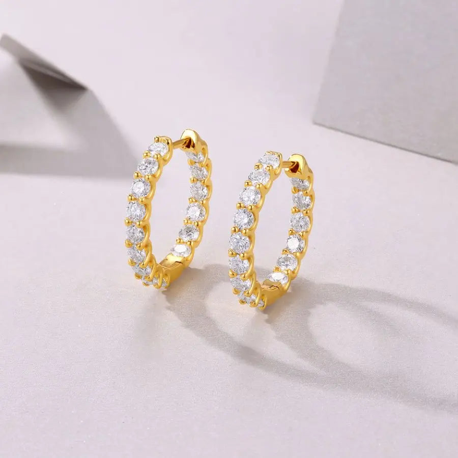 Gold hoop earrings with clear stones on a light gray background
