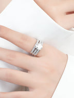 Silver ring with a diamond on a person's finger against a white background