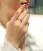 Gold signet-style ring with a bezel-set moissanite stone worn on a model’s hand in natural light