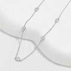 Silver necklace with small round pendants on a white background