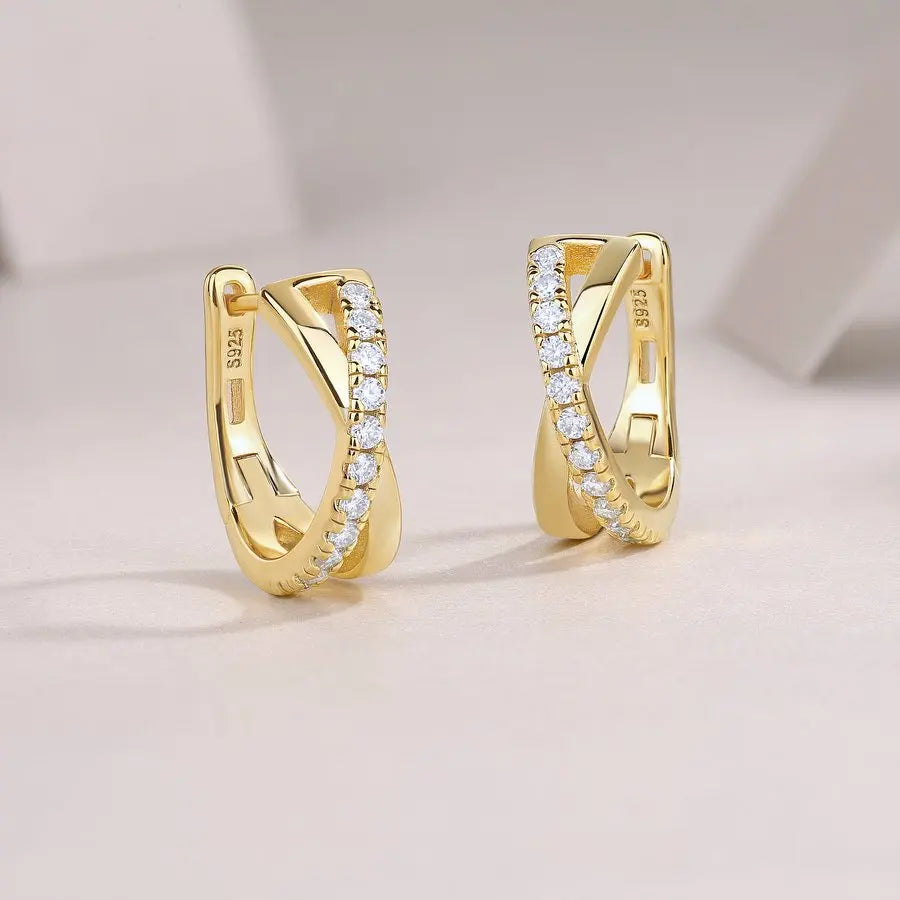 Gold hoop earrings with embedded diamonds on a light background