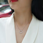 Close-up of a woman wearing a silver necklace with a circular pendant.