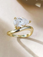 Gold ring with a pear-shaped diamond on a beige background