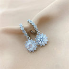 Silver earrings with clear gemstones on a beige fabric background
