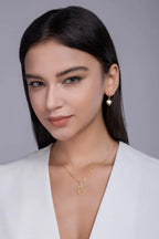 Woman wearing gold jewelry against a gray background