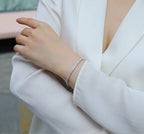 Person wearing a silver bracelet on a blurred background