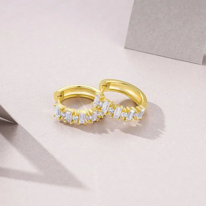 Gold hoop earrings with embedded diamonds on a light pink background