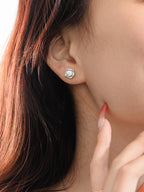 Close-up of a woman wearing a silver earring with a clear gemstone.