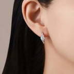 Close-up of an ear wearing a diamond earring with a neutral background