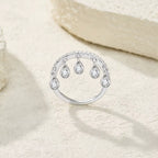 Silver ring with teardrop-shaped diamonds on a soft beige background