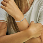 Close-up of a person wearing a silver bracelet on their wrist.