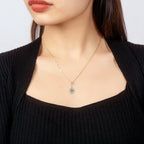 Necklace with a pendant worn by a person against a neutral background