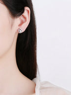 Close-up of a person wearing a floral earring on a plain background