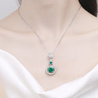 Silver necklace with a green gemstone pendant on a mannequin.
