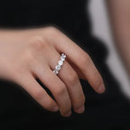 Silver ring with diamonds on a person's finger against a dark background