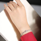 Diamond tennis bracelet worn on a wrist, featuring a continuous row of sparkling stones in a refined white metal setting
