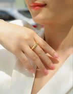 Gold signet-style ring with a bezel-set moissanite stone worn on a model’s hand in natural daylight