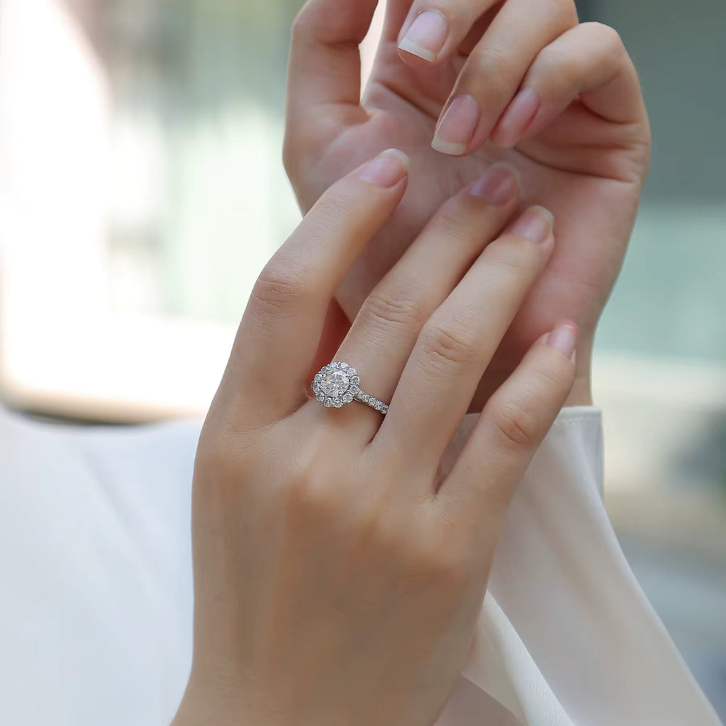 Close-up of a hand wearing a diamond ring with a blurred background