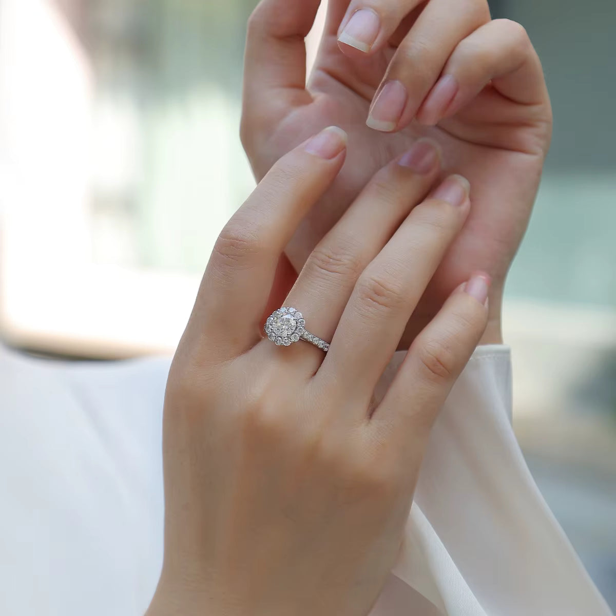 Close-up of a hand wearing a diamond ring with a blurred background