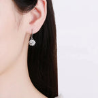 Silver floral earring worn by a person with dark hair on a white background