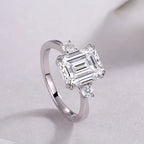 Diamond ring with a rectangular center stone on a light gray background