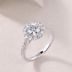 Silver ring with a large central diamond and smaller diamonds on a light background