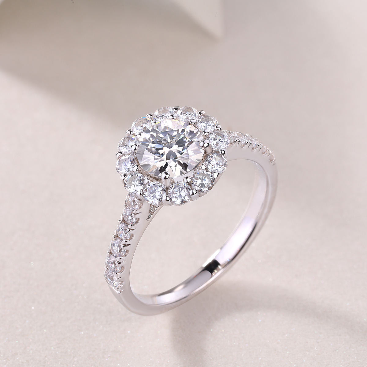 Silver ring with a large central diamond and smaller diamonds on a light background
