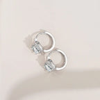 Silver hoop earrings with gemstones on a light beige background